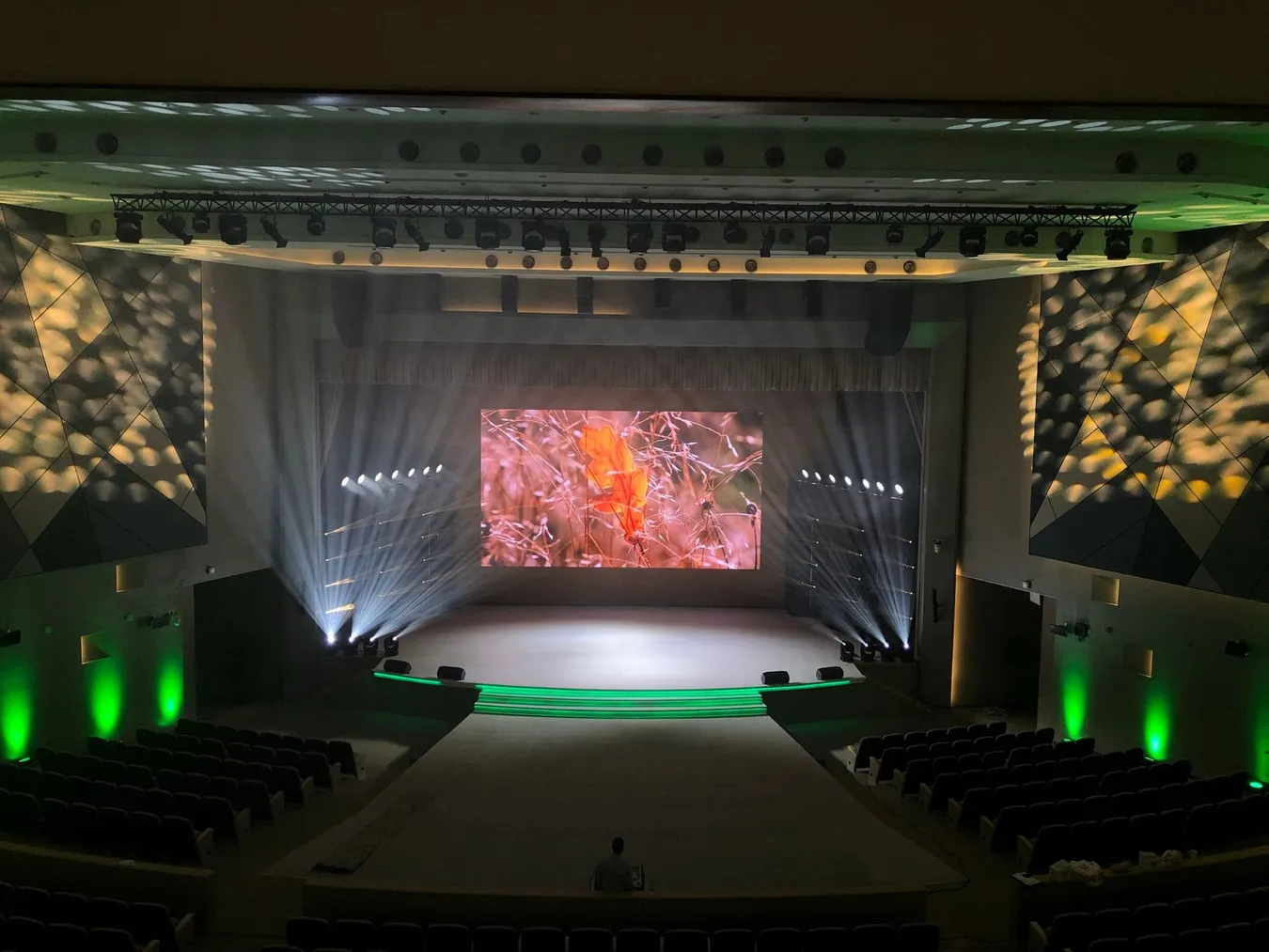 Auditorium with an LED screen above the stage and coloured stage lighting