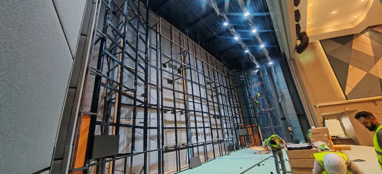 Technicians building the tall LED wall frame in the hall