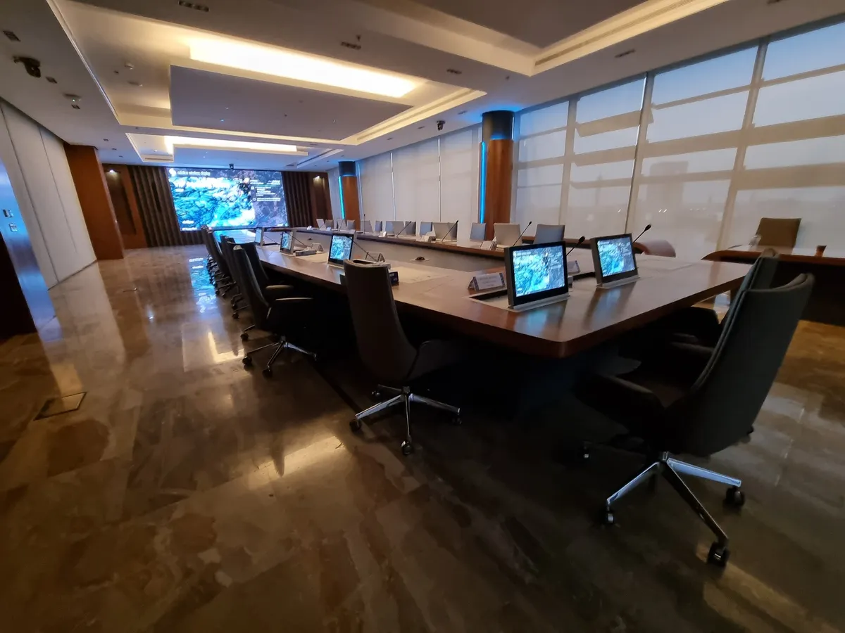 Long board table with monitors and an LED wall in the distance