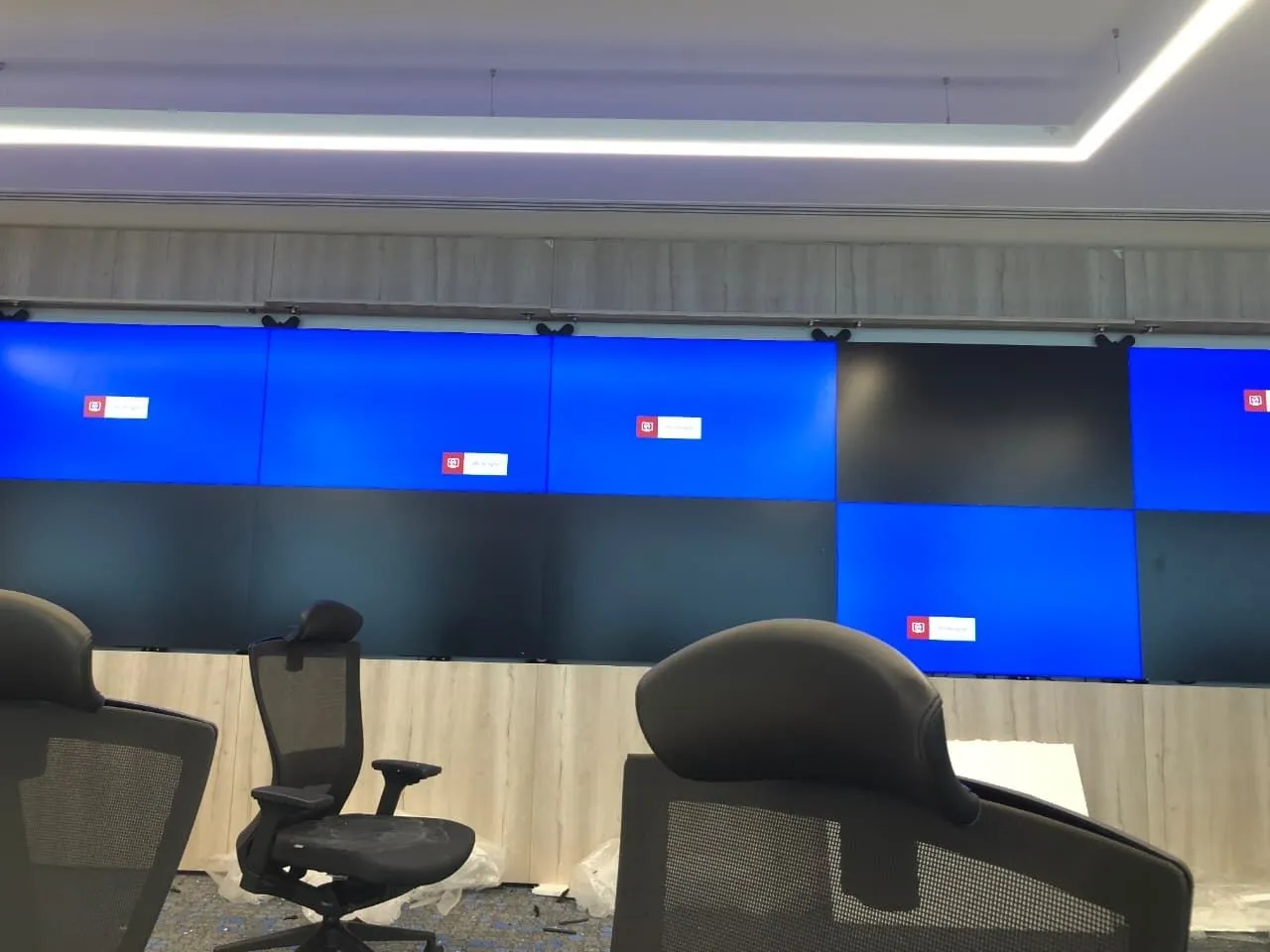 Control room video wall with two rows of displays and operator chairs