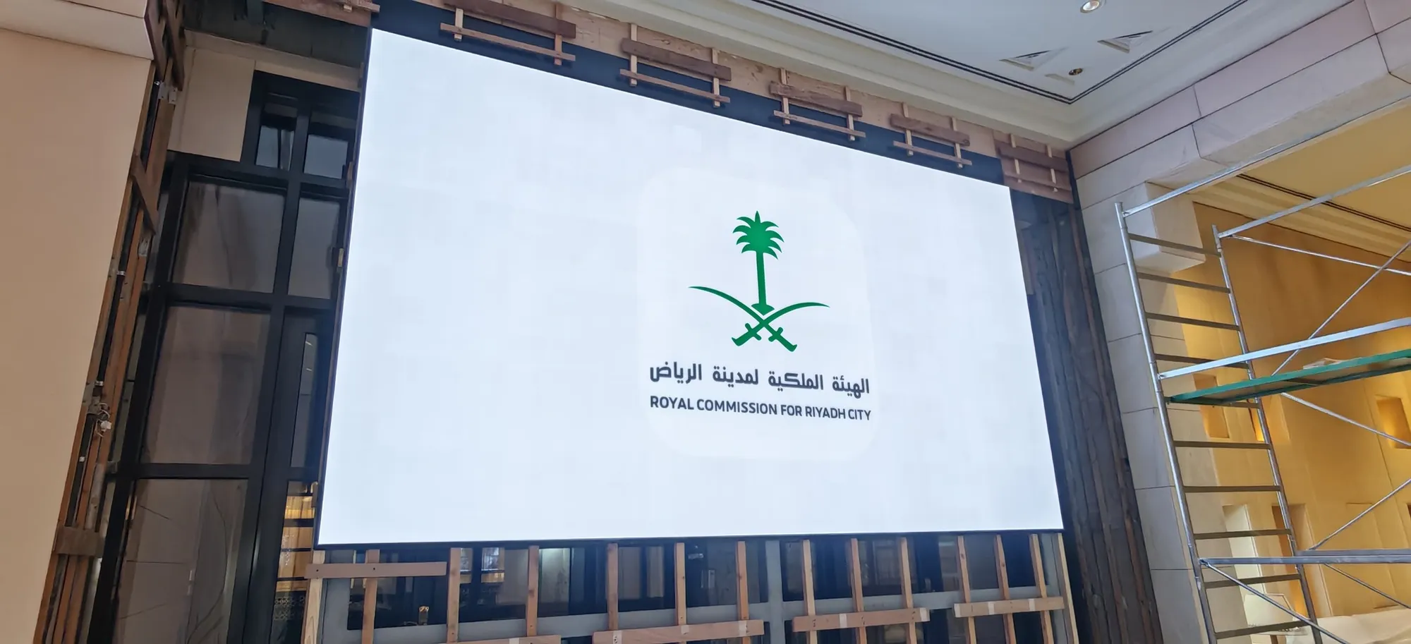 Large LED screen showing the Royal Commission for Riyadh City logo, in a hall under fit-out