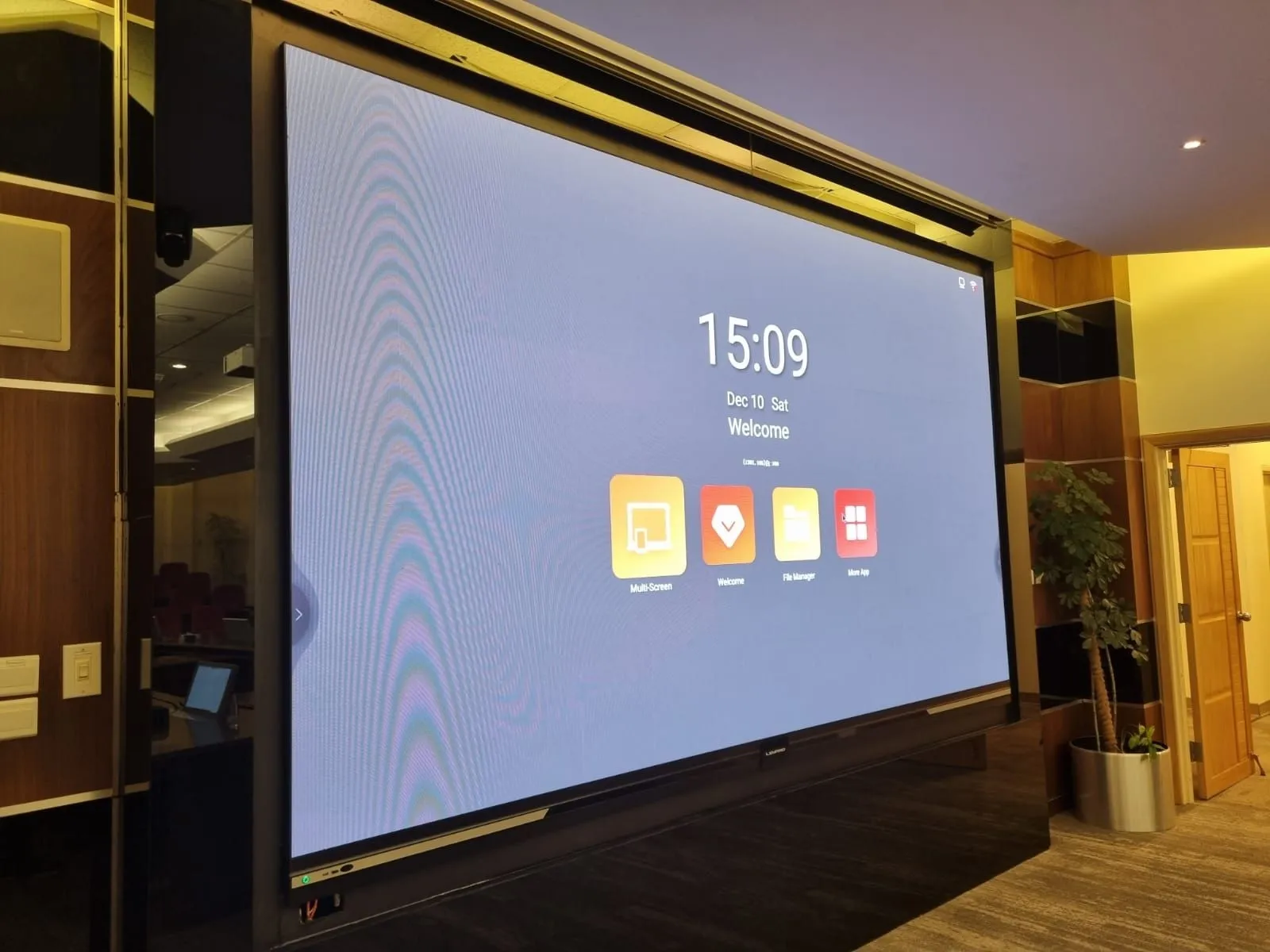 A large display on the wooden wall showing the home screen