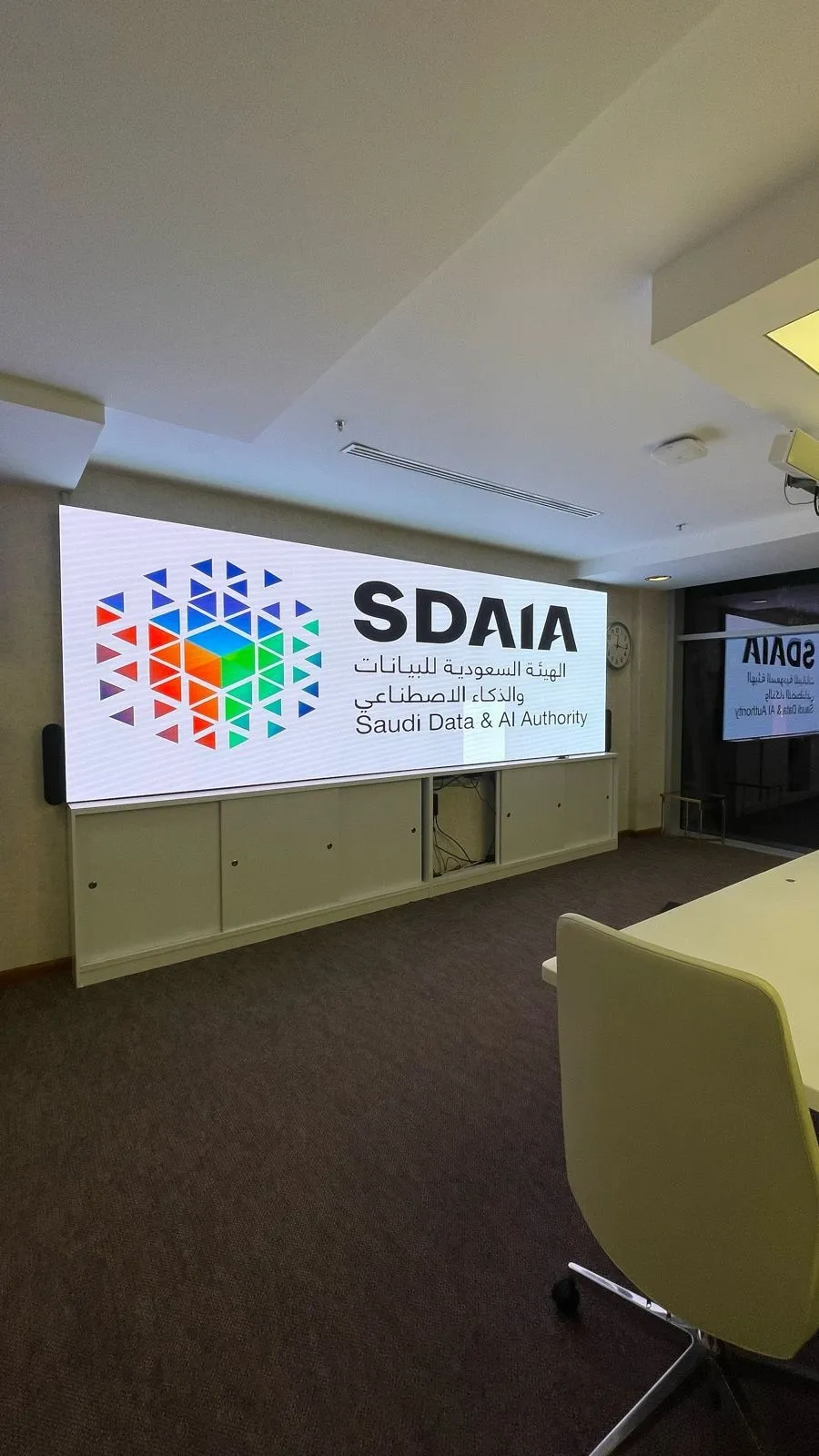 Meeting room wall display showing the SDAIA logo