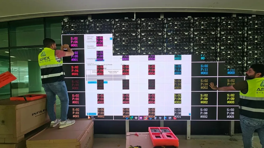 Two technicians checking a section of the LED wall against the test pattern