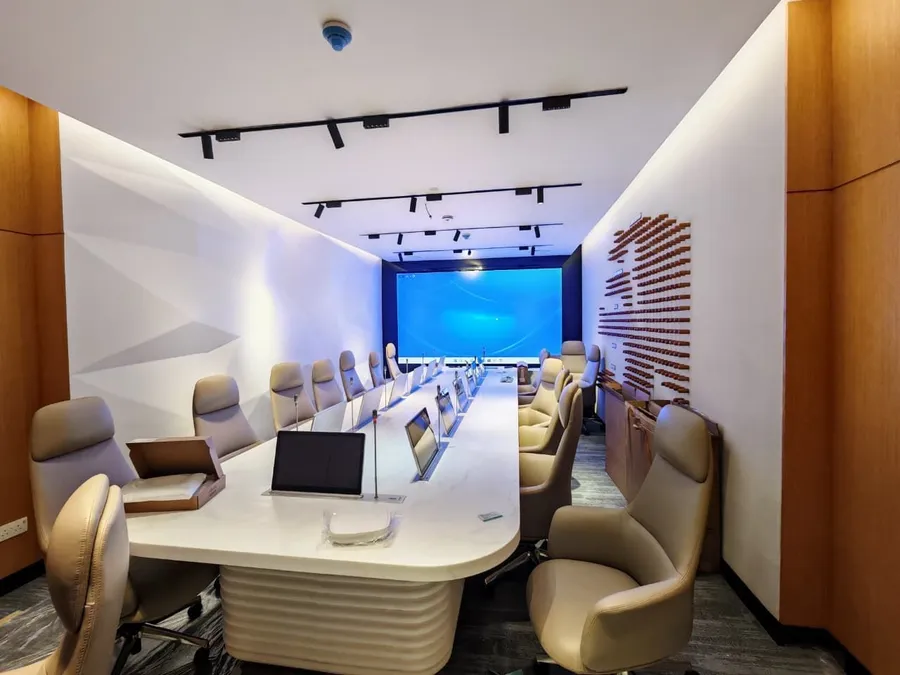 Boardroom with a long table, lift-up monitors and an LED wall