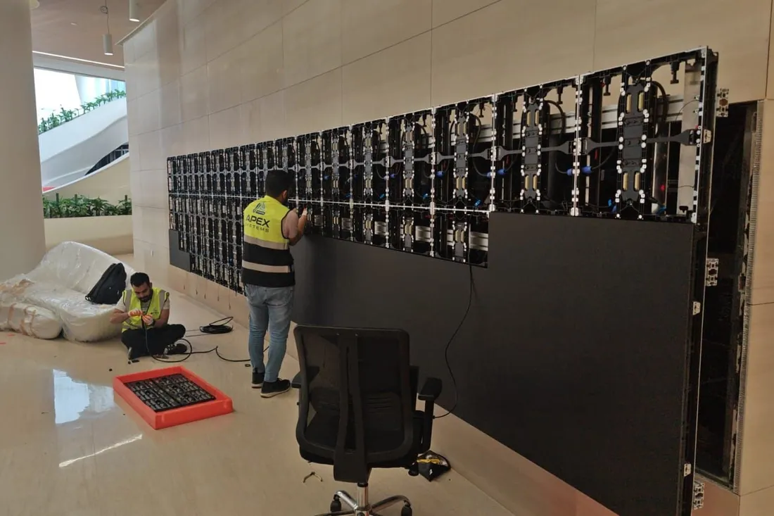 Technicians mounting LED cabinets on a wall in a building lobby